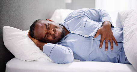 African Man Sitting On Bed Suffering