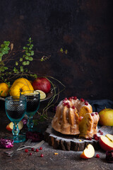 Homemade apple bundcake. Two glasses of red wine, bundcake, fruits on the dark brown table. Dark photography - 611674732
