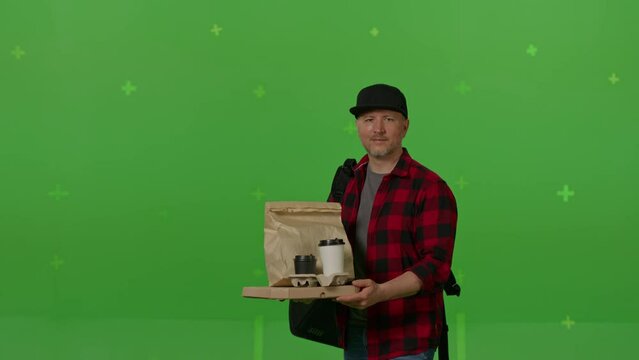 Caucasian male courier passing a box of pizza on green screen chroma key background. Man hold wireless bank payment POS terminal to process acquire credit card payment. Copy space mock up advertising