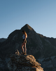 young girl having fun on a rock at sunset in the mountains during her trekking through the Pyrenees