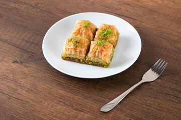 Turkish baklava with pistachio in plate.A plate baklava on wooden background,top view
