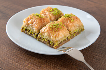 Turkish baklava with pistachio in plate.A plate baklava on wooden background,top view
