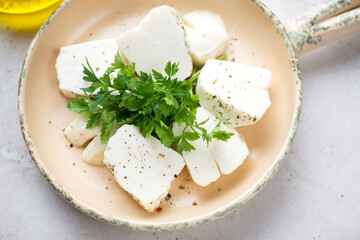 Beige serving pan with slices of haloumi cheese and fresh parsley, middle closeup, horizontal shot, selective focus