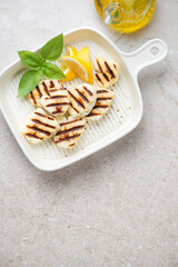 Beige serving tray with bbq halloumi cheese, vertical shot on a beige stone background, copy space, high angle view
