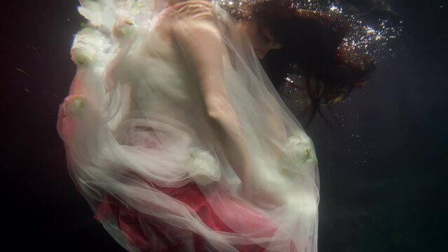 mysterious woman swimming underwater in magical depth of sea, slow motion
