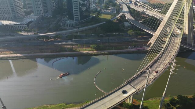 View of the Pinheiros river with modern buildings beside it and the famous Octavio Frias de Oliveira bridge in the city of S&atilde;o Paulo.