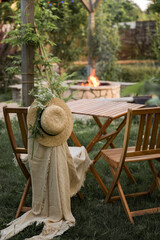 Wooden furniture in the garden against the backdrop of a fire on the patio. Among the branches of...
