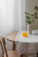 A glass of orange juice on a wooden round table on a cozy morning in the living room