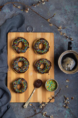 Homemade donuts on a wooden board, a cup of coffee and flowering branches on a grunge table. Top view - 611711152
