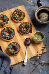 Homemade donuts on a wooden board, a cup of coffee and flowering branches on a grunge table. Close up - 611711324
