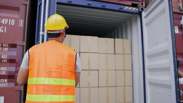Foreman and a worker help opening containers together and lifting the box  while female assistant check stock by computer at the transport warehouse. Cargo container and Transport Logistic concept