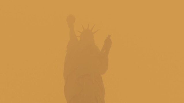 The Statue of Liberty in New York City covered in the smoke from the Canadian wildfires. Orange sky.