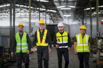 Engineers and technicians and workers, working together as a team, walking like an executive inside an industrial warehouse.