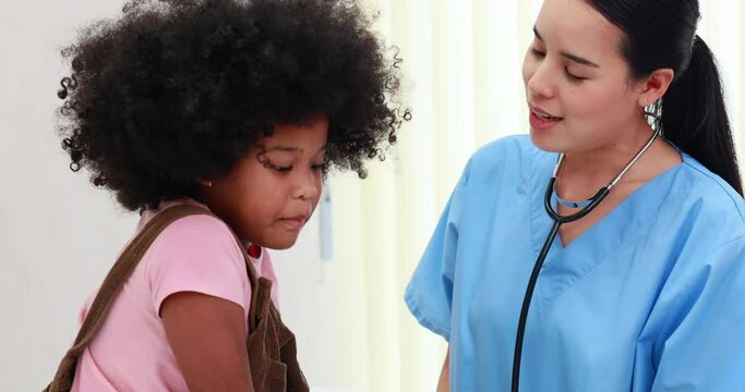 African american girl on bed at hospital clinic. Asian Pediatrics doctor examining little girl leg in bed at hospital clinic. Medicine and health care concept