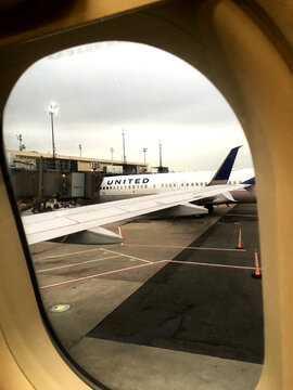 Newark, New Jersey, USA - 27 June 2018: Looking out an airplane window at a parked United Airlines commercial jet at Newark Airport (EWR) in New Jersey, United States. View our of airplane window.