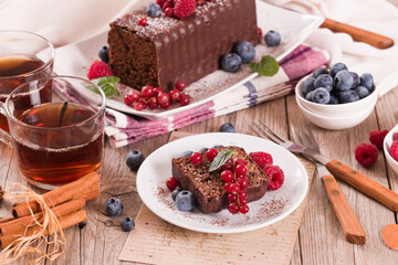 Chocolate sponge cake with fresh fruit on white dish. - 611723553