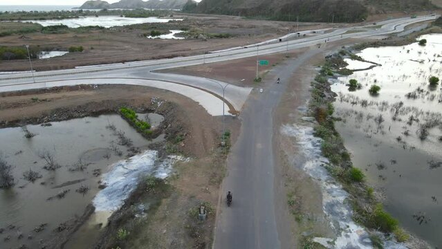 Man drives motorbike on new Highway in Lombok, Indonesia near Tanjung Aan Beach and Gerupuk Village