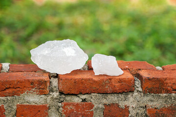 Cubes of alum lay on the floor of an orange brick wall. Alum can be used for many purposes such as...