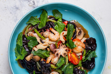 top view seafood and greens salad in a blue plate. Shrimp, octopus squid close-up.