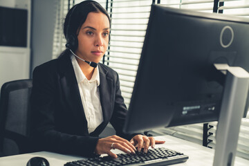 Competent female operator working on computer and talking with clients. Concept relevant to both...