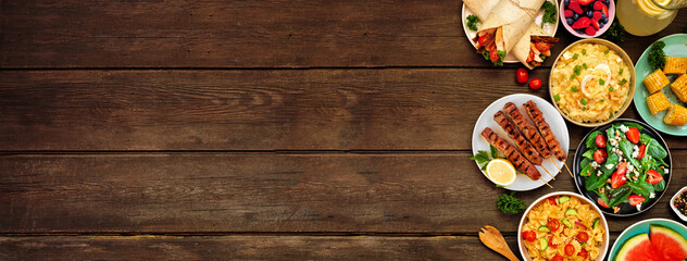 Summer food side border over a dark wood banner background. Assorted refreshing salads, fruit,...