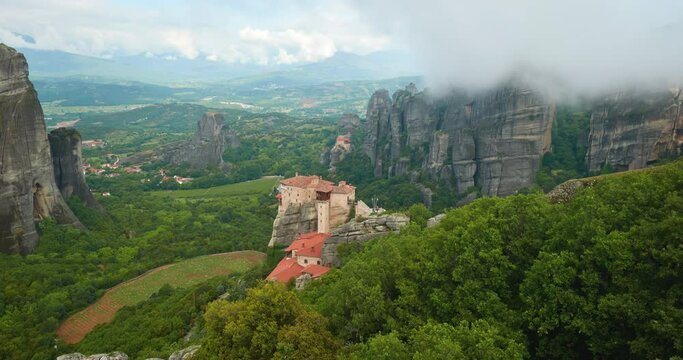 Meteora monastery complex in summer, Greece. Orthodox monastery on the rock, emerging from morning misty to sunny day, timelapse video. UNESCO site, Greece. 