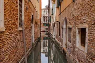 Fototapeta na wymiar Intimate Canal View Amidst Venice's Residential Walls