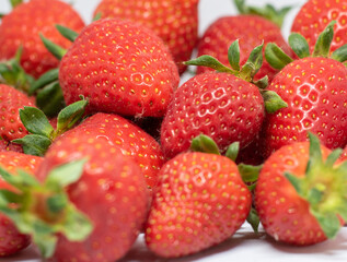 Beautiful red ripe strawberries are seen harvested on a white background and ready to be consumed.
