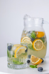 lemonade in a glass and a jug on a white background. Summer refreshing drink. Cold detox water with lemon