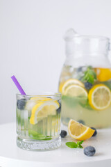 lemonade in a glass and a jug on a white background. Summer refreshing drink. Cold detox water with lemon