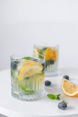 lemonade in a glass and lemons on a white background. Summer refreshing drink. Cold detox water with lemon