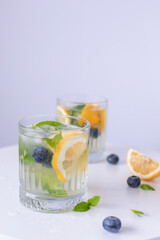 lemonade in a glass and lemons on a white background. Summer refreshing drink. Cold detox water with lemon