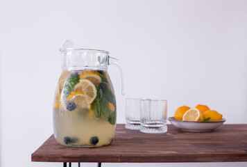 lemonade in glass and jug on wooden table outdoors. Summer refreshing drink. Cold detox water with...