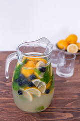lemonade in a glass and lemons on a wooden table outdoors. Summer refreshing drink. Cold detox water with lemon