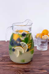 lemonade in glass and jug on wooden table outdoors. Summer refreshing drink. Cold detox water with lemon