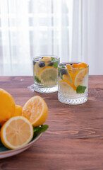 lemonade in a glass and lemons on a wooden table outdoors. Summer refreshing drink. Cold detox water with lemon