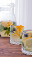 lemonade in glass and jug on wooden table outdoors. Summer refreshing drink. Cold detox water with lemon