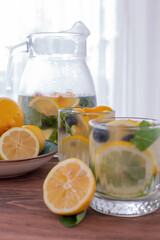 lemonade in glass and jug on wooden table outdoors. Summer refreshing drink. Cold detox water with lemon