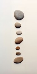 Art de galets minimaliste avec une série d'empreintes de pas de galets ressemblant à des rochers dans le sable menant à l'océan