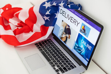 delivery man in red shirt with hygienic mask, holding goods order in package parcel out from laptop computer with warehouse background. order online, delivery service on covid-19 coronavirus epidemic