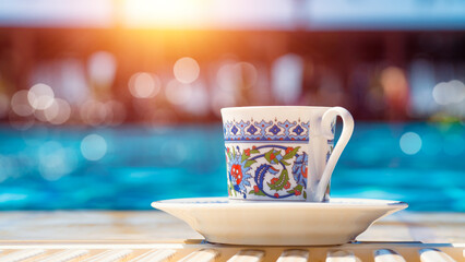 Closeup photo of a Turkish coffee in a porcelain mug by the swimming pool in a hot summer day in Antalya, Turkey..