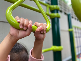 hands of girl hanging at playground.close up hands of girl playing, hanging walk along the monkey bars.