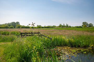 Obraz premium Idyllic view of a fence and small windmill in the Dutch polder landscape near Gouda, Holland