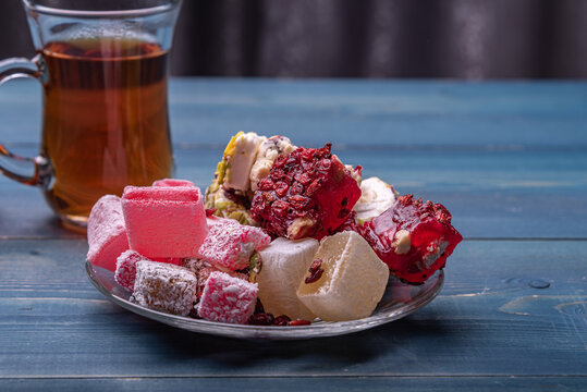 Turkish delight, lokum in a plate on a wooden desk against the armudu with turkish tea.