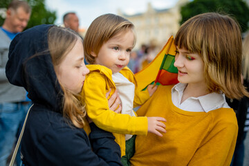 Two big sisters and a cute toddler boy holding tricolor Lithuanian flag on Lithuanian Statehood...