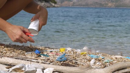 CLOSE UP: Female hand picking up washed up plastic waste on a beautiful seashore. Eco-friendly beach visit and cleaning action to brighten up summer lounging on holidays at amazing Adriatic seaside.