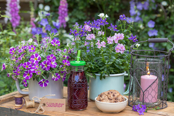 Tischdekoration mit Saft-Flasche, Cookies und Sommerblumen in Emaille-Töpfen