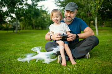 Father and son watching and navigating a drone. Cute toddler boy helping his father to operate a...