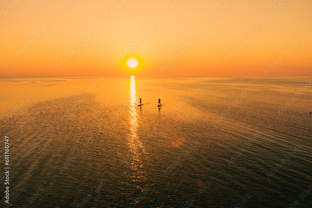 Canvas Prints Aerial view of two people on stand up paddle boards on quiet sea at sunset. Warm summer beach vacation holiday. - Canvas Prints
