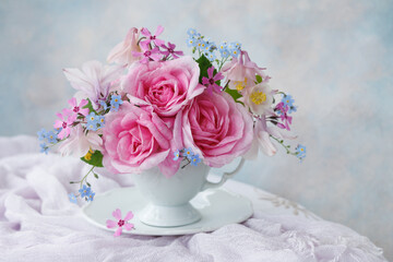 Bouquet of spring and summer flowers in a cup on the table,  rose, aquilegia, forget me not...